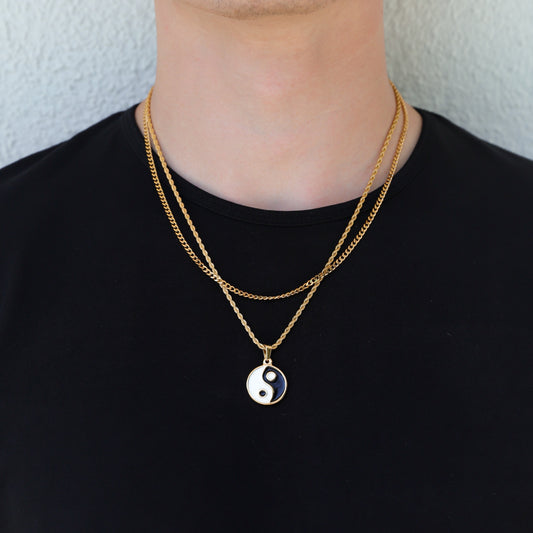 Gold yin-yang pendant necklace set with layered chain, worn on black shirt